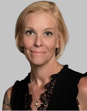 Professional headshot of Lydia with blonde hair, wearing a black top.