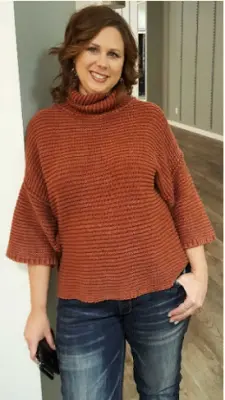 A woman in a cozy knit sweater posing indoors with a smile.
