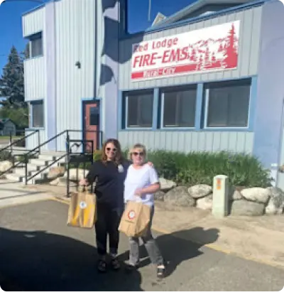 Two women holding bags outside the Red Lodge FIRE-EMS building.